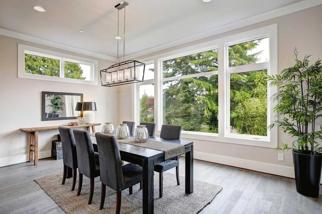 A couple reviews mortgage paperwork with a lender at a table covered in documents and a laptop.